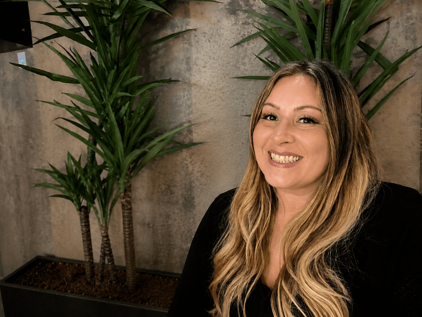 Misty Treviño smiling, beside a plant